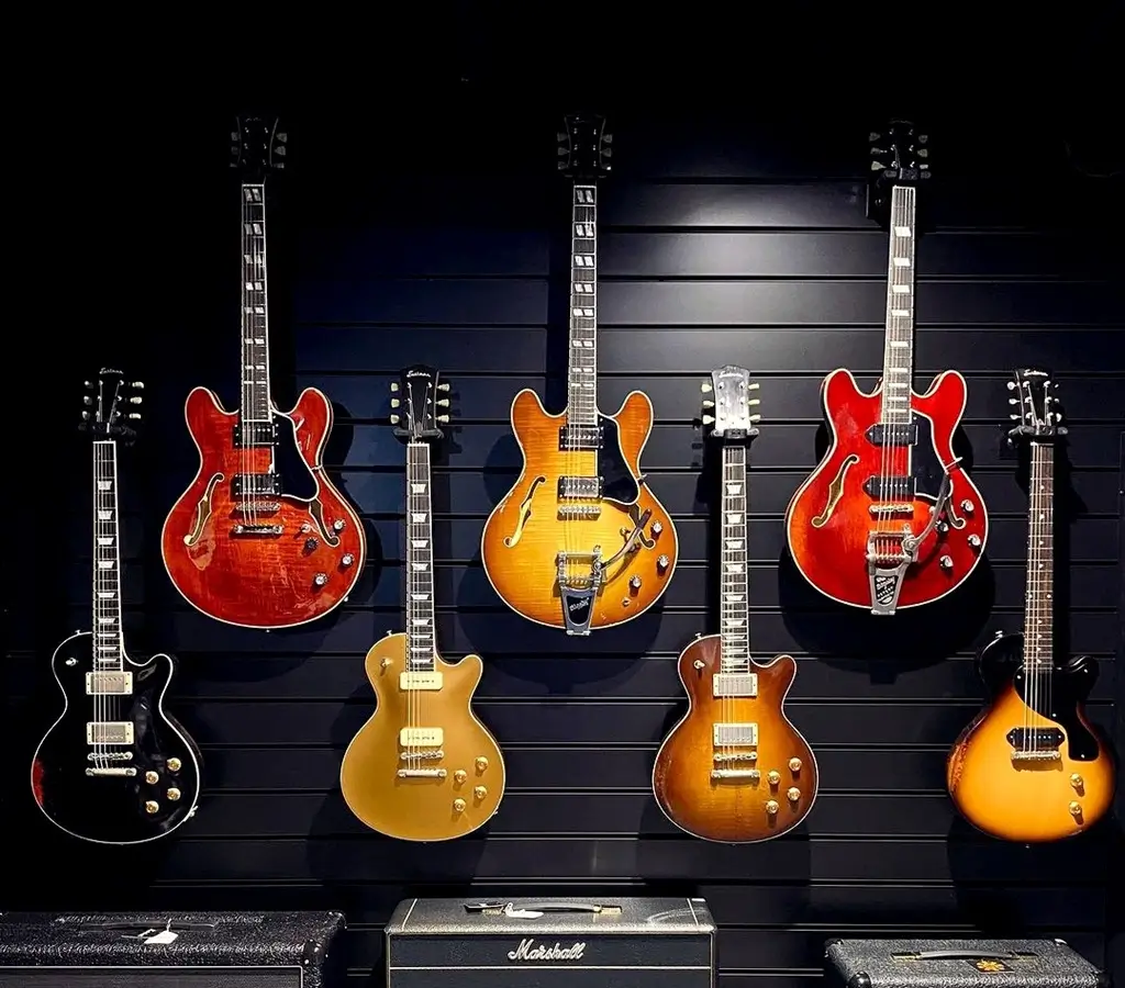 Customized music shop guitars on black slatwall with black inserts.