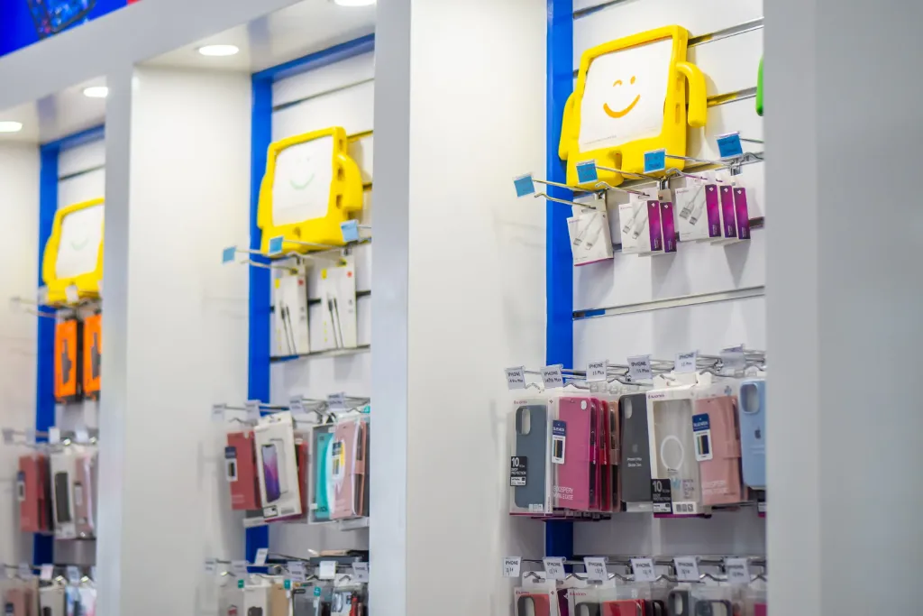 Close-up of white slatwall panels with adjustable hooks displaying phone cases and mobile accessories at GR Phones Adelaide CBD.