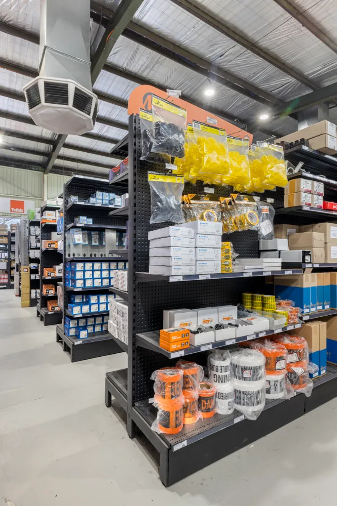 Black volcano board gondola end bay with display hooks, adjustable shelves, and electrical accessories in the AWM Airport West trade warehouse.