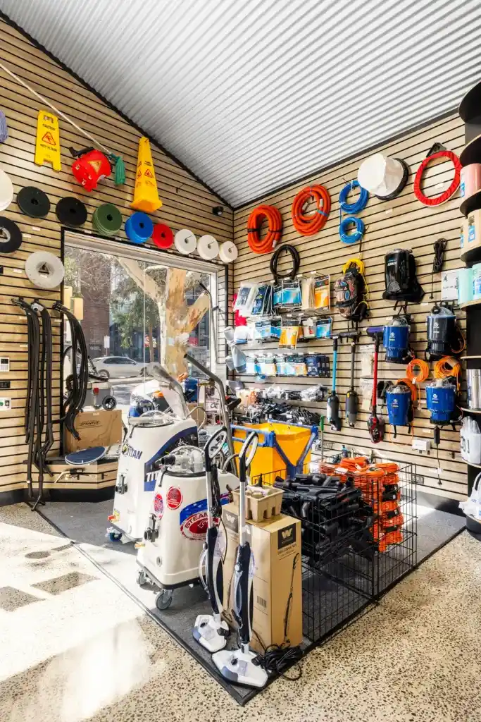 Professional cleaning equipment showroom display with floor scrubbers, vacuum cleaners, metal retail dump bins, and walnut slatwall display systems.