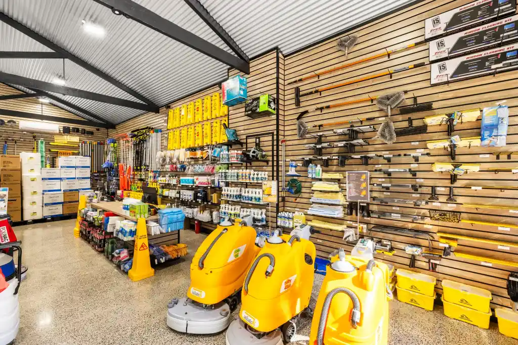 Walnut slatwall display with cleaning equipment, floor scrubbers, pressure washers, accessories, and retail shelving in a professional cleaning supplies showroom.