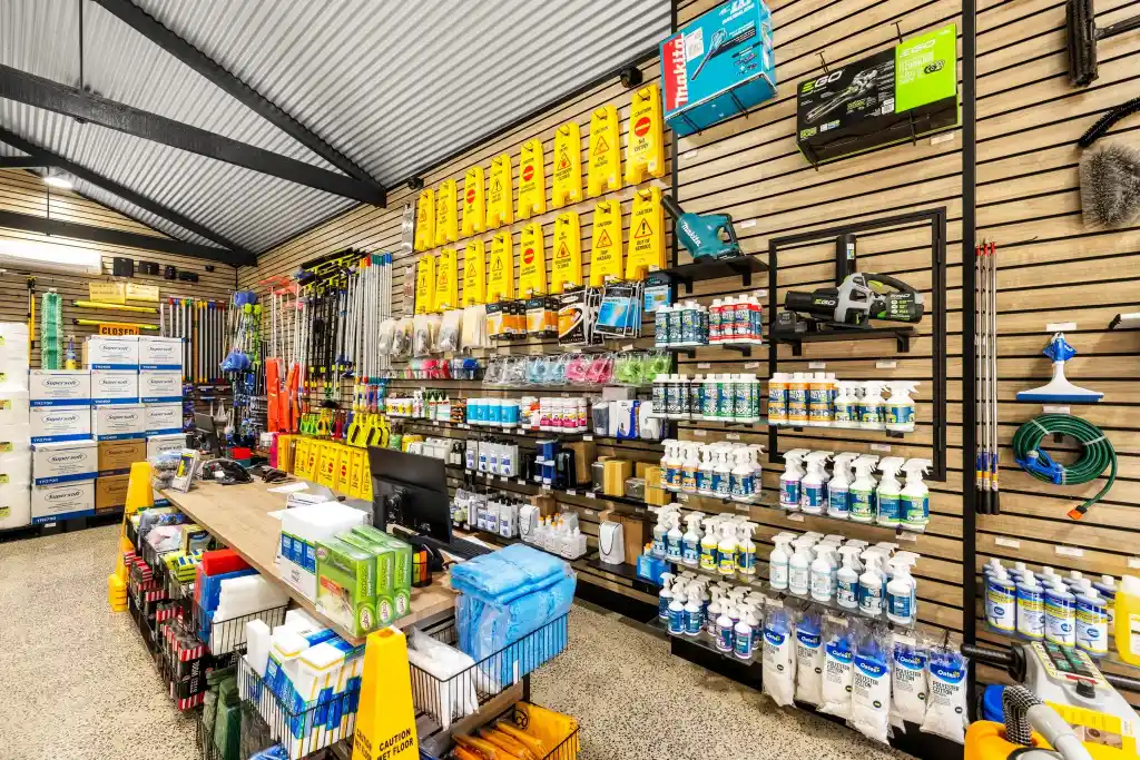 Walnut slatwall display with cleaning products, long-handled tools, retail shelving, and customer service counter in a professional cleaning equipment showroom.
