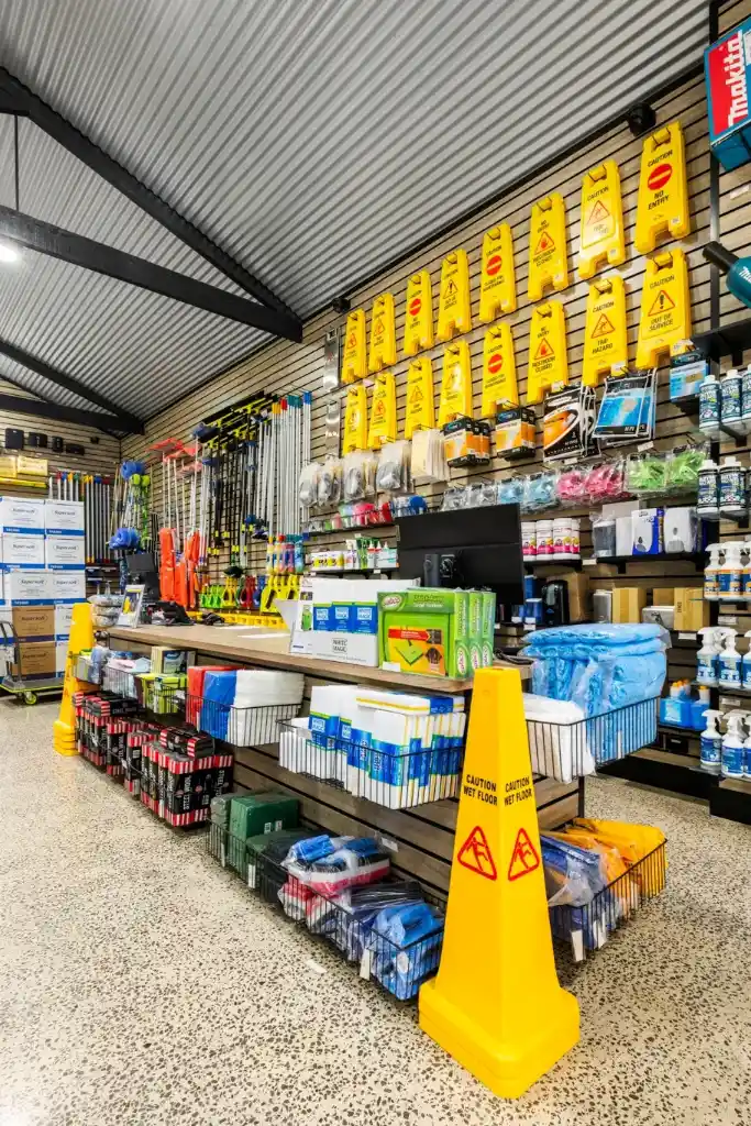 Professional cleaning supplies retail display featuring walnut slatwall panels, cleaning products, and a customer service counter in a commercial trade showroom.