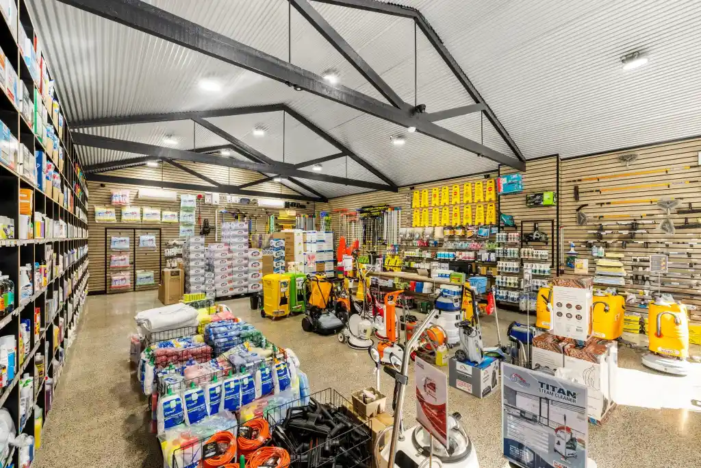 Walnut slatwall display with cleaning equipment, floor scrubbers, pressure washers, accessories, and retail shelving in a professional cleaning supplies showroom.