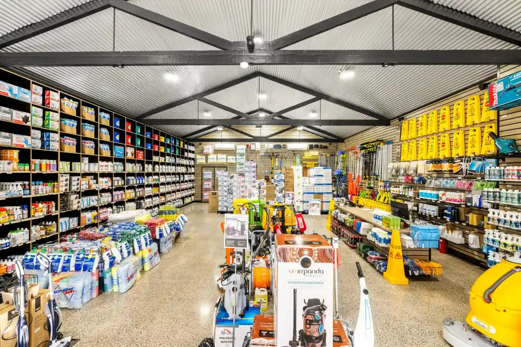 Professional cleaning equipment trade showroom fitted with walnut slatwall display panels, retail shelving, display hooks, and commercial cleaning products by Dinya Shop Fittings.