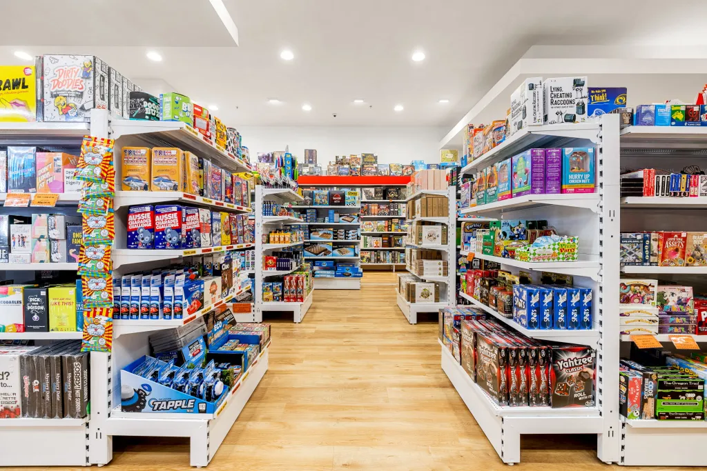 Games World Doncaster store aisle featuring white plain panel gondola shelving with organised displays of board games, puzzles, toys, and collectibles.