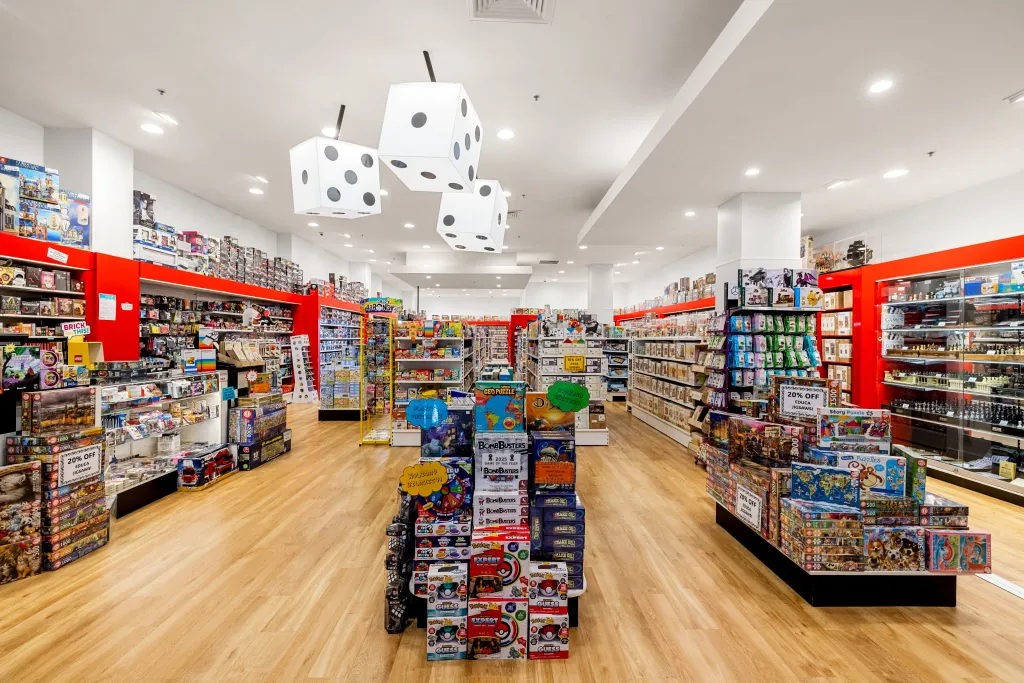 Wide view of Games World Doncaster featuring white plain panel gondola shelving, glass display cabinets, and organised product aisles.